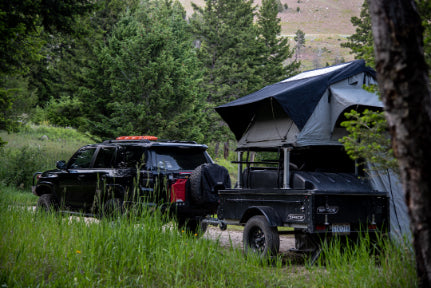 Black space trailer with tent on top surrounded by grass