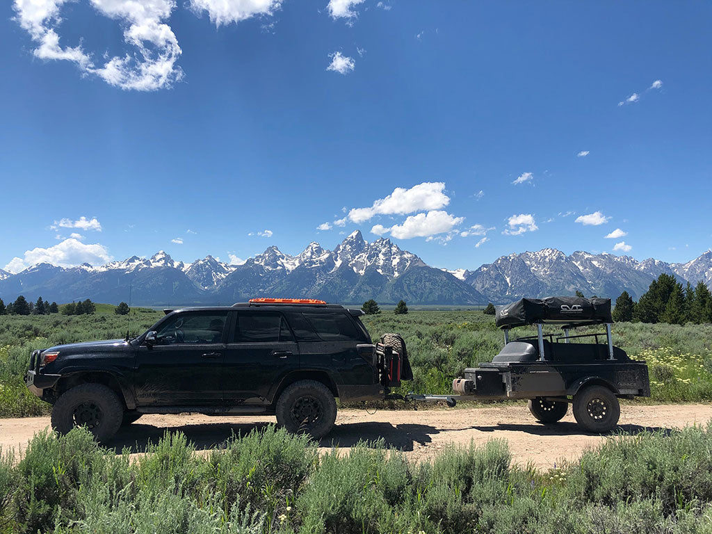 Gray space trailer with black vehicle pulling it with mountains behind